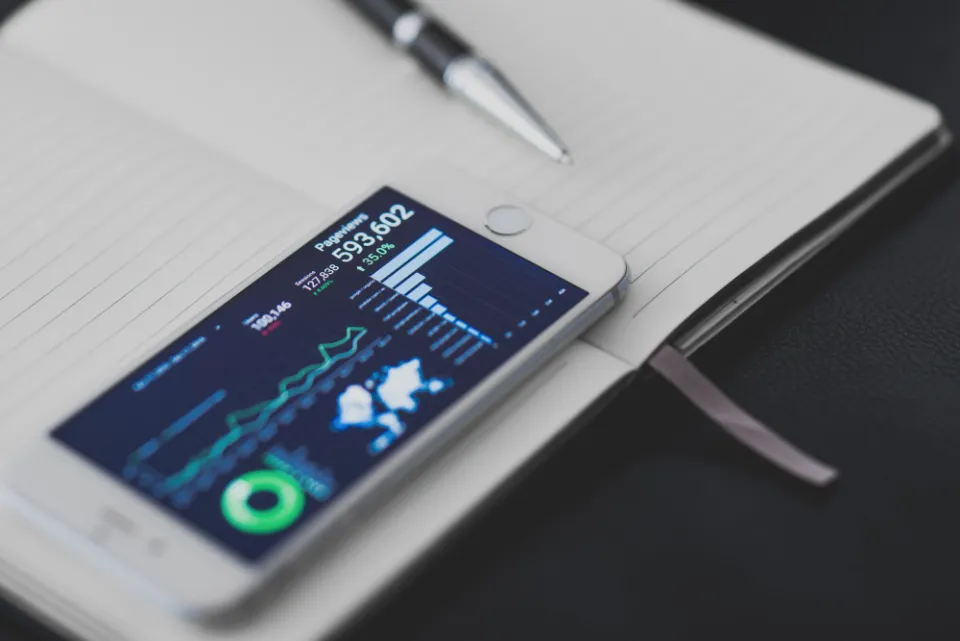 A phone showing an analytics dashboard on an open notebook