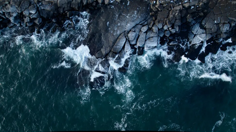 Waves breaking on the black basalt coast of Jeju, seen from above