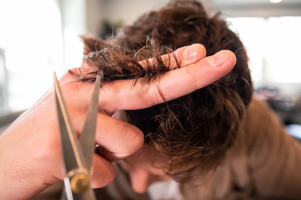 Stylist cutting short brown hair with scissors